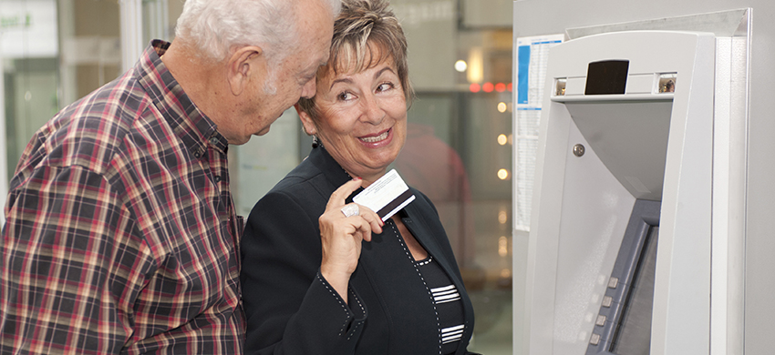 Senior Hispanic couple withdrawing money from ATM
